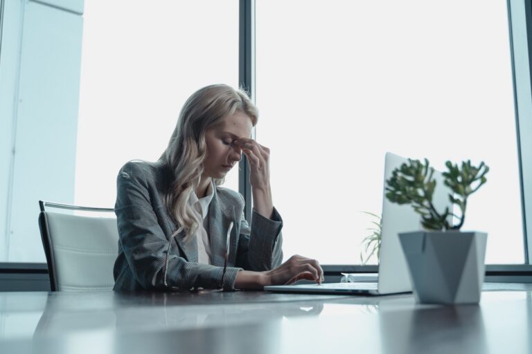 Professional experiencing stress while working at a laptop in an office