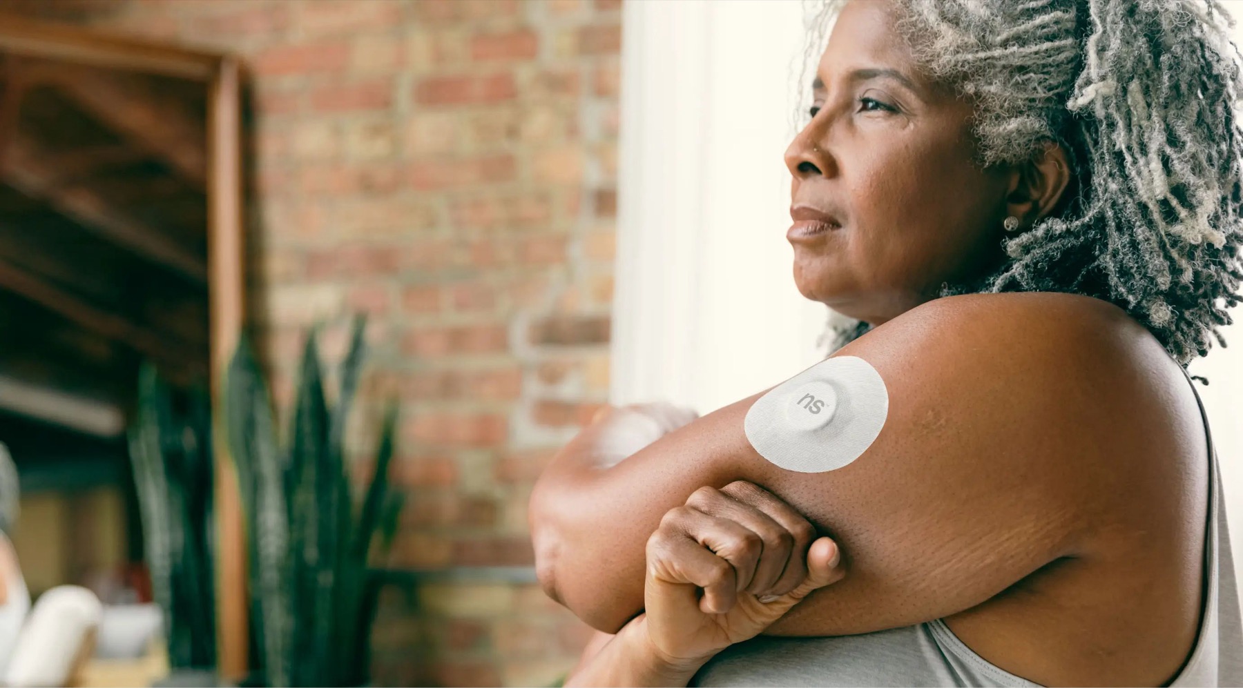 Adult wearing a continuous glucose monitor on the upper arm