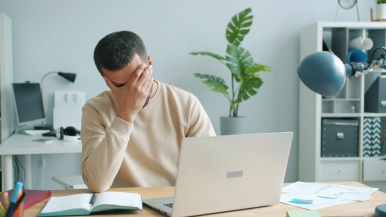 Tired professional pausing at a laptop in a bright home office