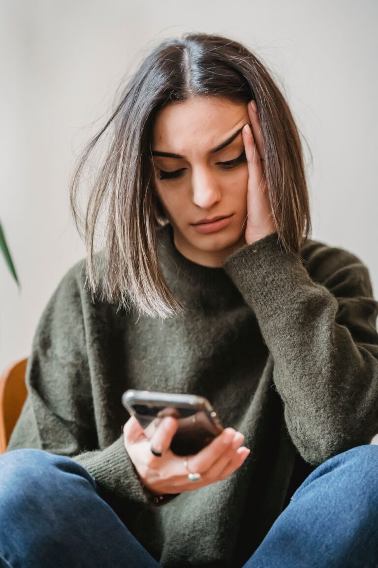 Concerned woman looking at her smartphone at home